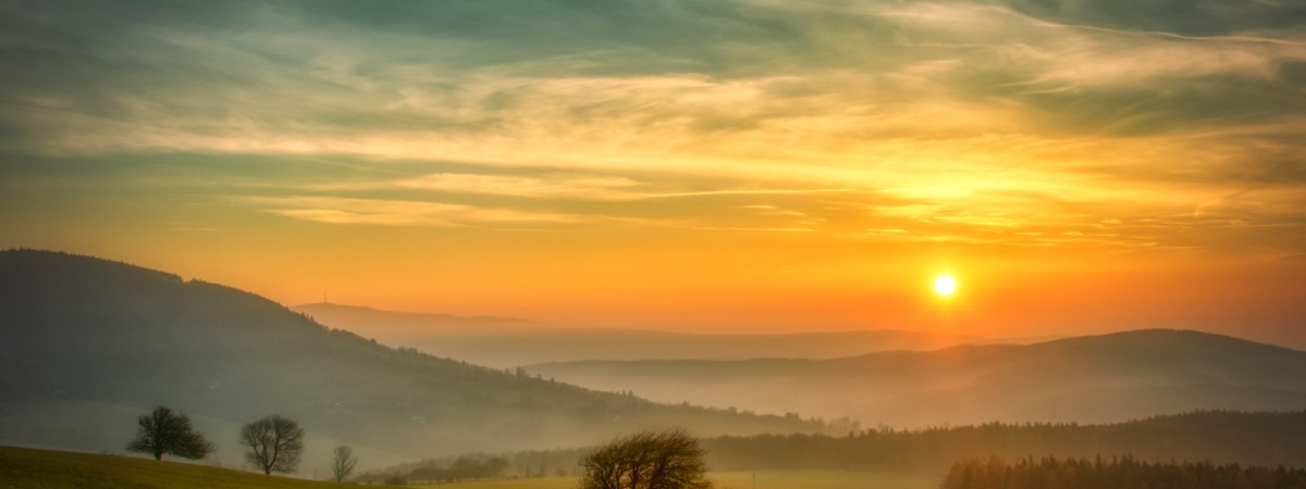 Scenic hilly landscape with solitary trees during sunset, view to the valley, blue sky with high clouds,sun. Autumn evening. White Carpathians mountains,Czech republic.
