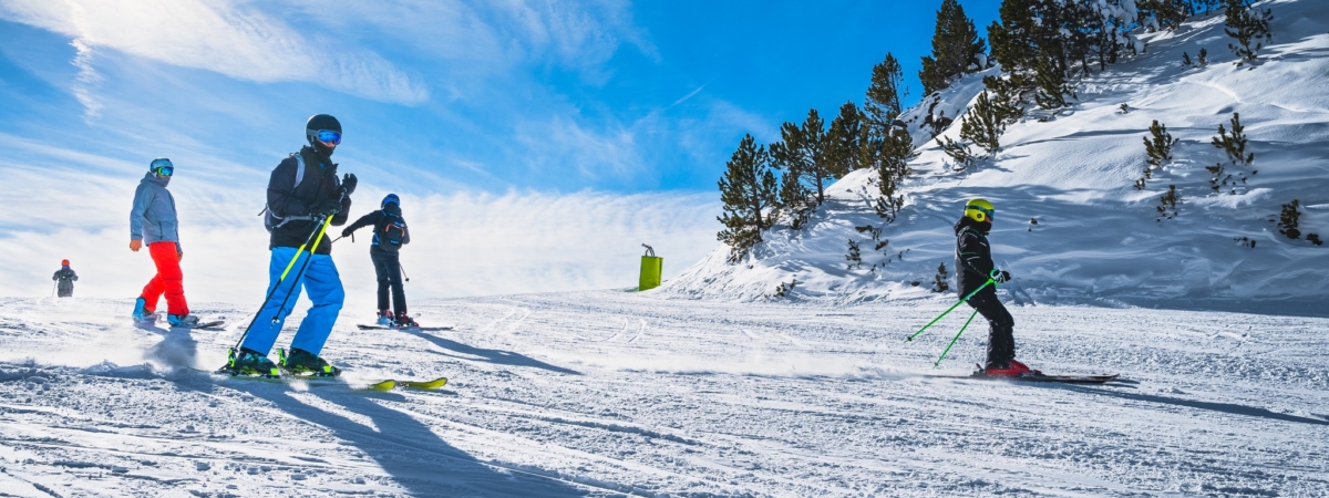 Group of people skiing and snowboarding down the ski slope or piste in Pyrenees Mountains. Winter ski holidays in El Tarter, Grandvalira, Andorra